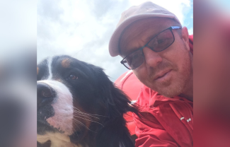 A man smiling for the camera. Next to him is a dog