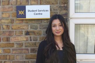 A woman standing in front of a sign saying 'Student Services Centre'
