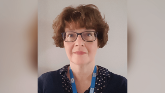 A woman wearing an NHS lanyard, smiling