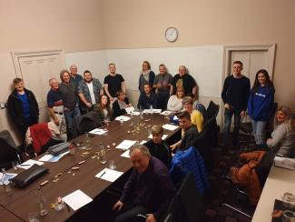 A group of people sitting and standing around a conference table, smiling for the camera