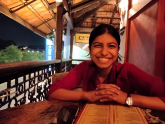 A young woman at a restaurant table, smiling