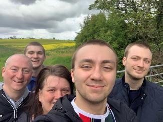 A young man with his family around him, in a field