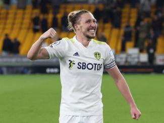 A footballer on a pitch smiling and punching the air