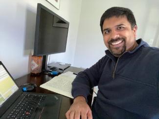 A man sitting at a desk in front of a computer, smiling