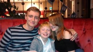 Two older children and one younger child smiling for the camera