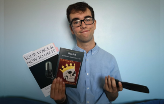 A young man holding two books in one hand and a remote control in the other