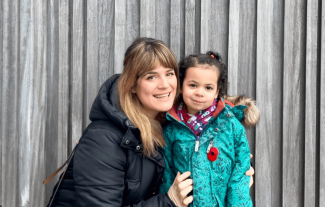 A woman with her daughter smiling at the camera