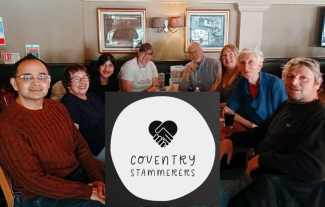 A group of people sitting around a cafe table, smiling for the camera, with a logo in between them saying 'Coventry Stammerers'