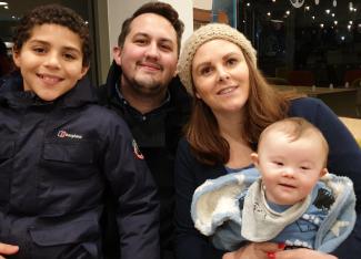 A family with two young children smiling for the camera