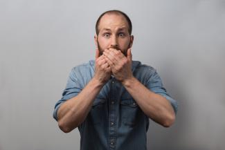 A man covering his mouth with his hands in staged surprise