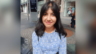 A woman sitting outside, looking at the camera and smiling