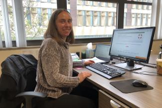 A woman sitting at a desk at work smiling for the camera