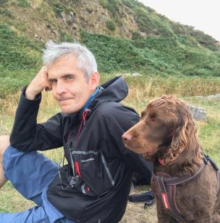 A man sitting on a hillside with his dog