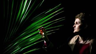 A woman looking at a houseplant and reaching out to touch it