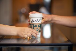 A Starbucks coffee cup handed over the counter