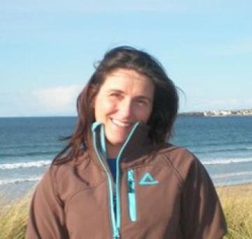 A woman smiling, with a beach backdrop