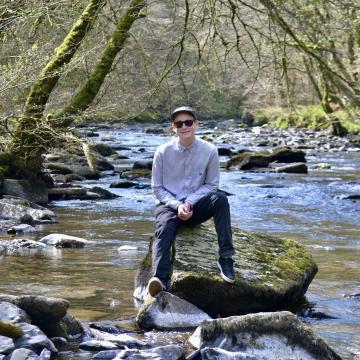 A man sitting on a rock in the middle of a stream