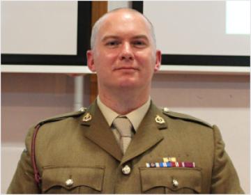 A man in a soldier's uniform, smiling