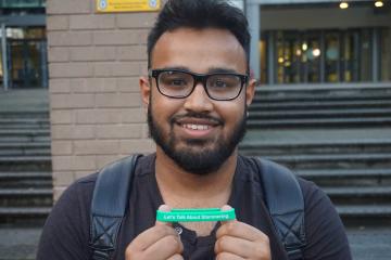 A man smiling for the camera and holding a wristband
