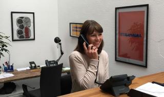 A woman at a desk speaking into a phone