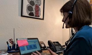 A woman sitting in front of a laptop computer and wearing a headset