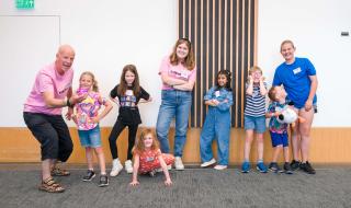 A group of children smiling, with two grown ups 