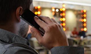 The back of a man's head as he speaks into a mobile phone. 