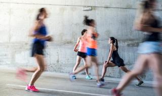 Women running in an urban setting, with one doing stretches