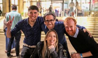 Three men and a woman huddled together and smiling