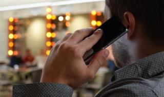 The back of a man's head as he holds a mobile phone to his ear