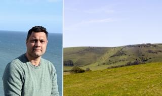 A man with the ocean behind him, next to a field in the Sussex countryside