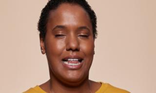 A woman with her eyes closed, trying to talk.
