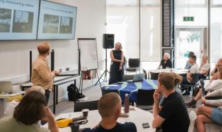Two presenters speaking to a class of adults
