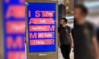 A man standing next to a digital advertisement