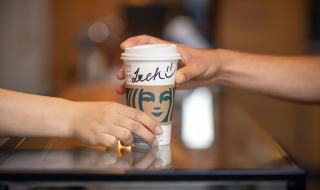 A Starbucks coffee cup handed over the counter