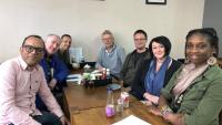 Adults sitting around a cafe table looking at the camera and smiling