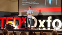 A young man on a stage speaking publicly to an audience