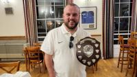 A man holding a trophy, smiling for the camera