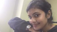 A young woman smiling, with her face resting on her arm