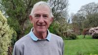 A man standing in a garden and smiling