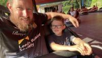 A man and his son sitting in a bumper car and smiling