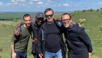 Four men standing together and smiling in the coountryside