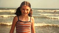 A girl on beach with waves behind her