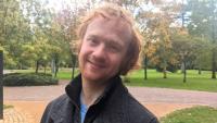 A man in a park looking at the camera and smiling