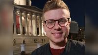 A man smiling for the camera with London's National Gallery behind him