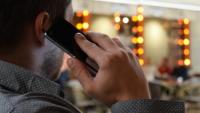 The back of a man's head as he speaks into a mobile phone. 