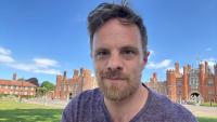 A man smiling, with Hampton Court Palace in the background