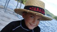 A young boy in a straw hat beside a river