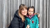 A woman with her daughter smiling at the camera