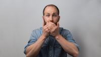A man covering his mouth with his hands in staged surprise